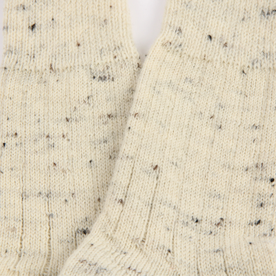 Close-up of a textured beige fabric with black specks