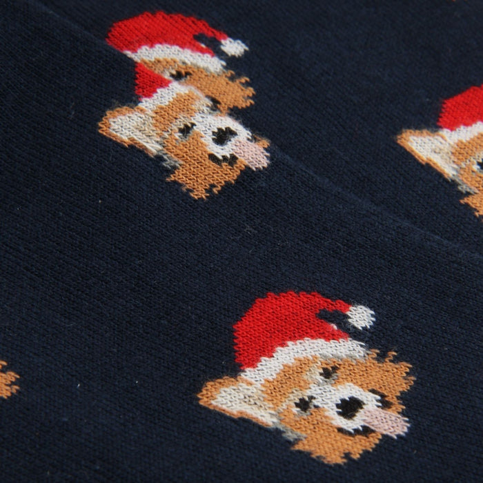 Navy blue fabric with a knitted in face of a corgi dog wearing a red Santa hat pattern.