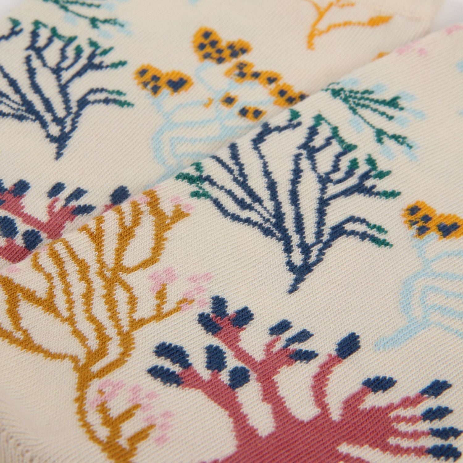 Close-up of a fabric with colorful coral reef pattern on a beige background