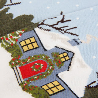 Cross-stitched house design on fabric with a snowy background