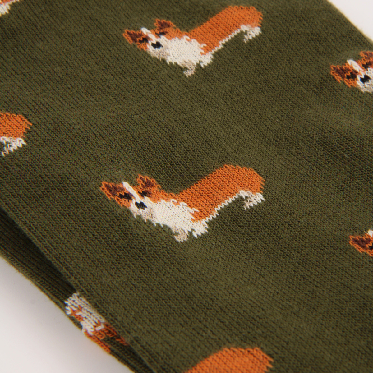 Close-up of a knit fabric in dark olive green with a repeating pattern of corgi dog illustrations in orange, white, and black.