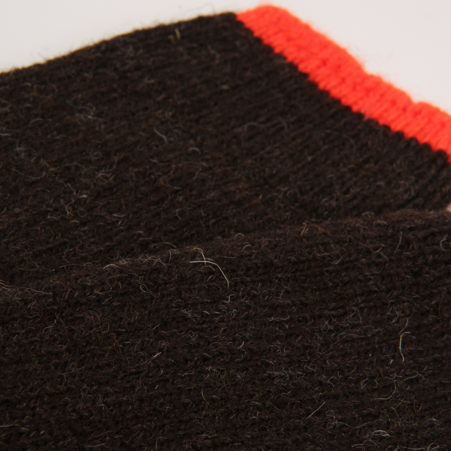 Close-up of a dark brown textured knit sock with a bright orange cuff, shown against a plain white background.