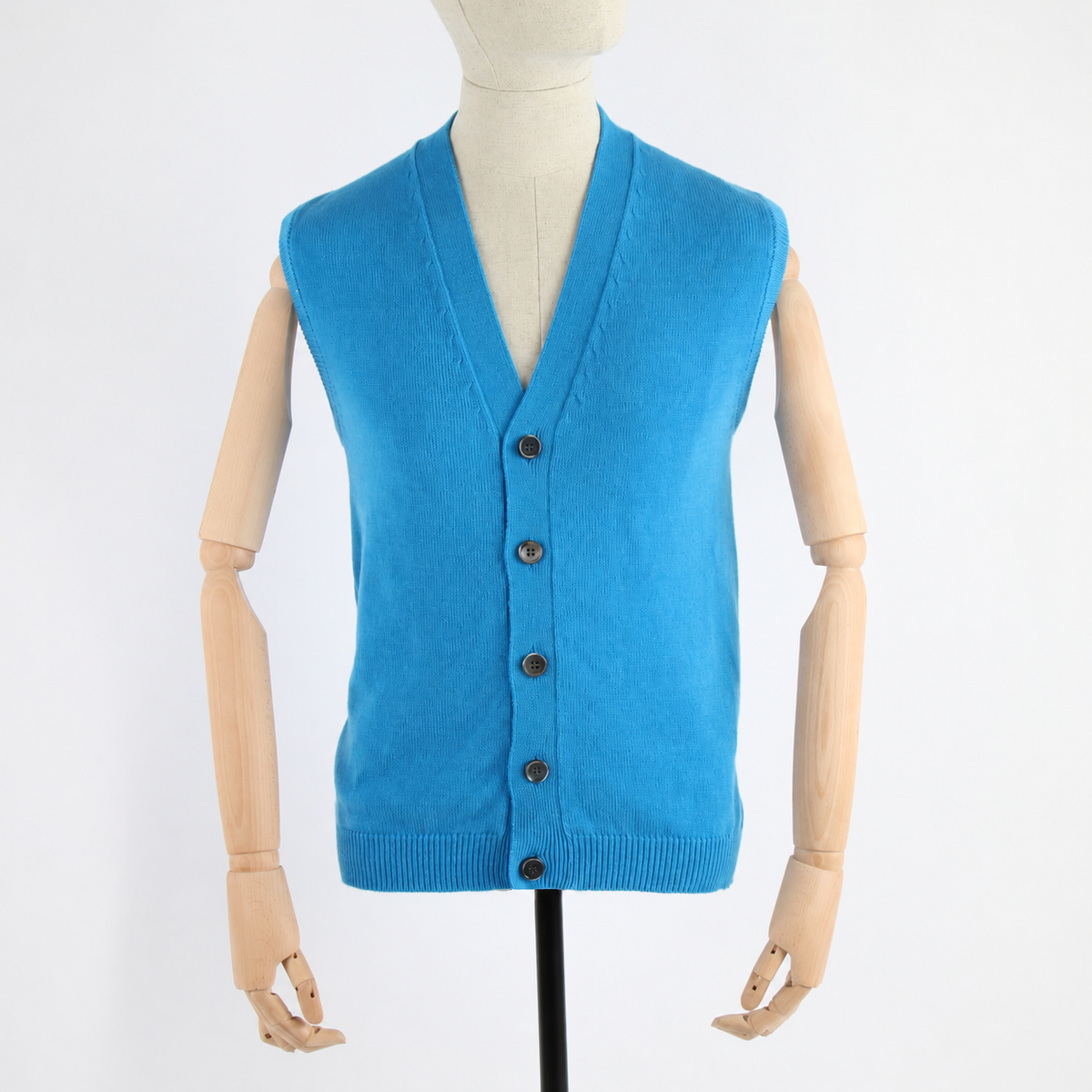 A bright blue knit cardigan vest displayed on a wooden mannequin torso against a plain white background.