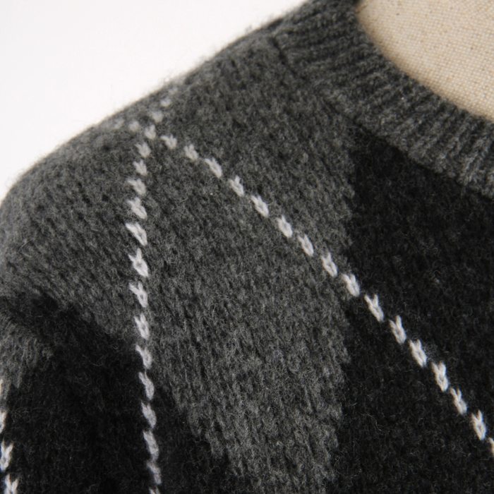 Close-up of a dark gray knitted sweater with white stitching detail.
