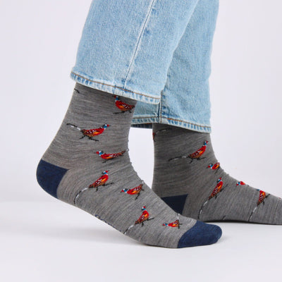 Grey socks with red and blue pheasant bird pattern worn with light blue jeans on a white background