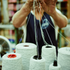 Person handling yarn with spools in the foreground