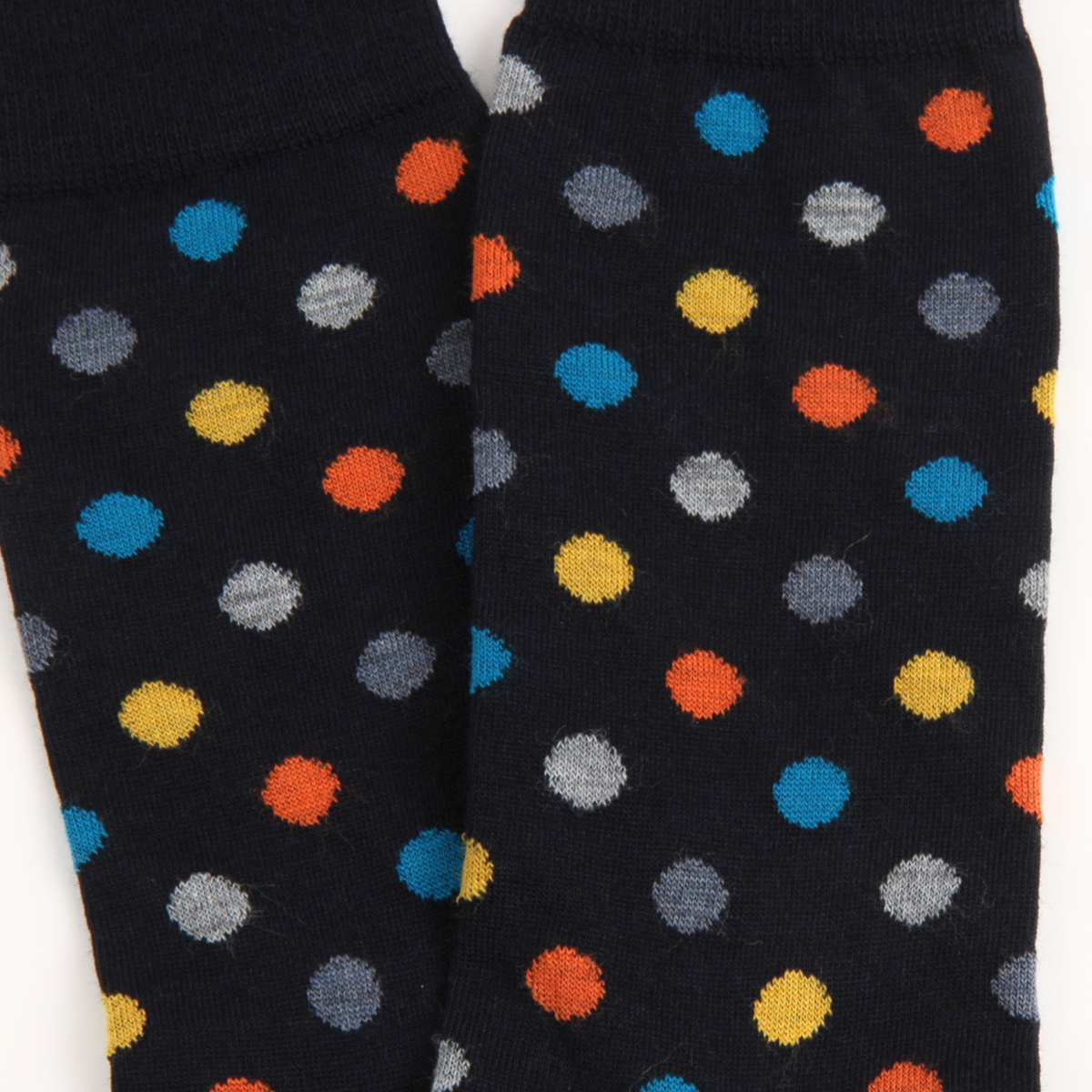 Close-up of a pair of navy knit socks with a colorful polka dot pattern, featuring blue, orange, yellow, gray, and white dots.