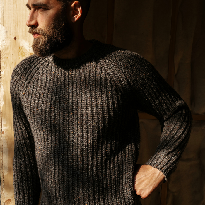 Man wearing a brown ribbed sweater against a neutral background