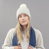 person wearing Beige knit beanie with a grey pom-pom on a grey  background