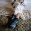 person wearing William Morris socks on a bed