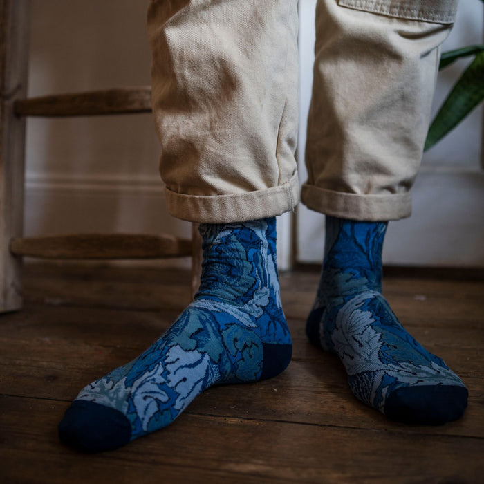 person wearing William Morris socks on a dark wood floor