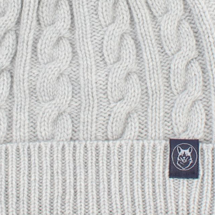 White knit beanie with a brand label on a white background