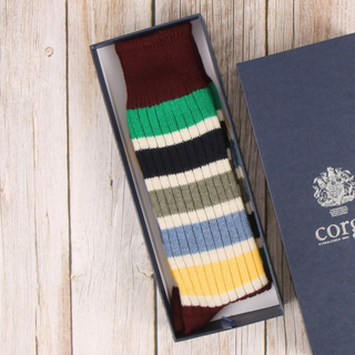 Colorful striped sock in a branded box on a wooden surface
