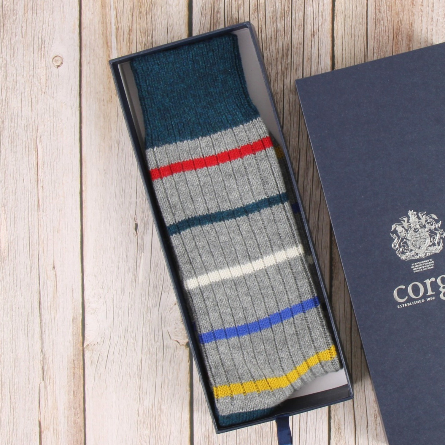 Colorful striped sock in a branded box on a wooden surface
