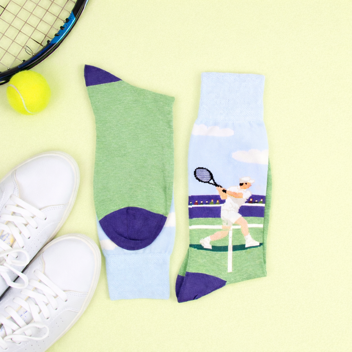 Tennis-themed socks with a player design, tennis racket, and ball on a light green background