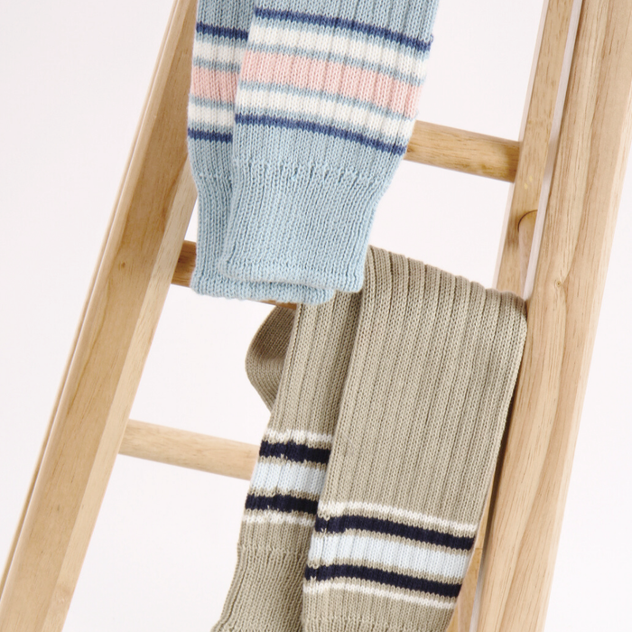 Two pairs of striped socks on a wooden ladder against a white background