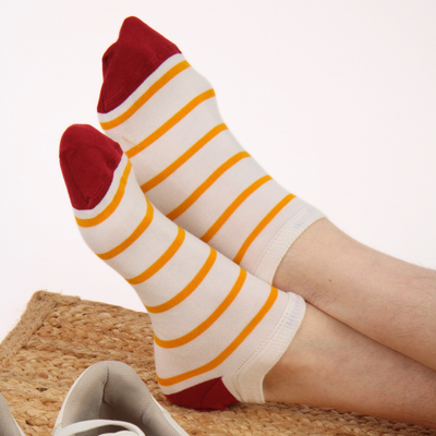 White socks with red tops and yellow stripes worn by a person on a white background