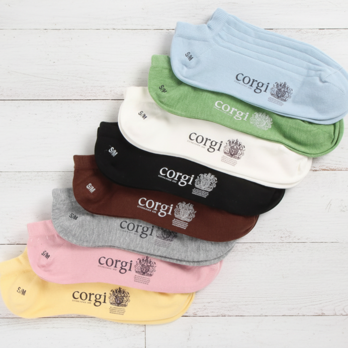 Set of colorful socks with 'corgi' branding on a light wooden surface