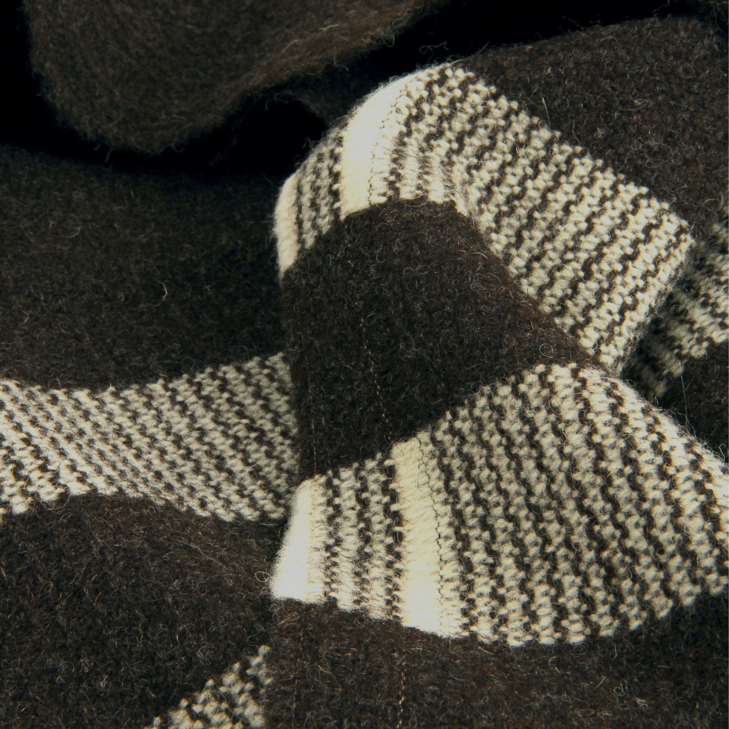 Close-up of a knitted scarf with a checkered pattern in black and white.