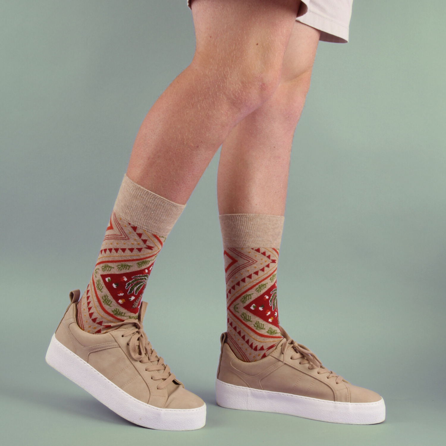 Person wearing patterned socks with beige sneakers on a gradient background