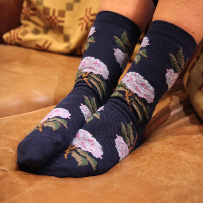 Floral-patterned socks on a person sitting on a brown couch.