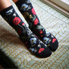 Black socks with colorful floral patterns on a textured surface