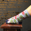 Floral-patterned sock on a wooden stool with a dark background