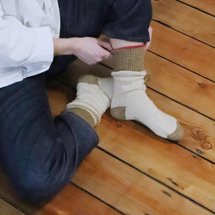 Person wearing white socks with brown toes and cuffs on a wooden floor.