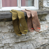 Two pairs of socks, one green and one brown with orange accents, hanging on a stone ledge.