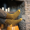Person wearing yellow and black striped socks with a stone fireplace in the background