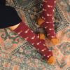 Maroon socks with Corgi dog pattern worn on a patterned rug
