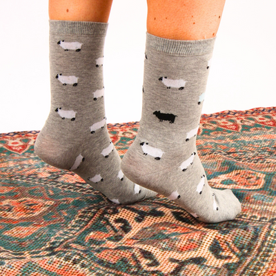 Gray socks with black and white sheep pattern worn on a patterned rug