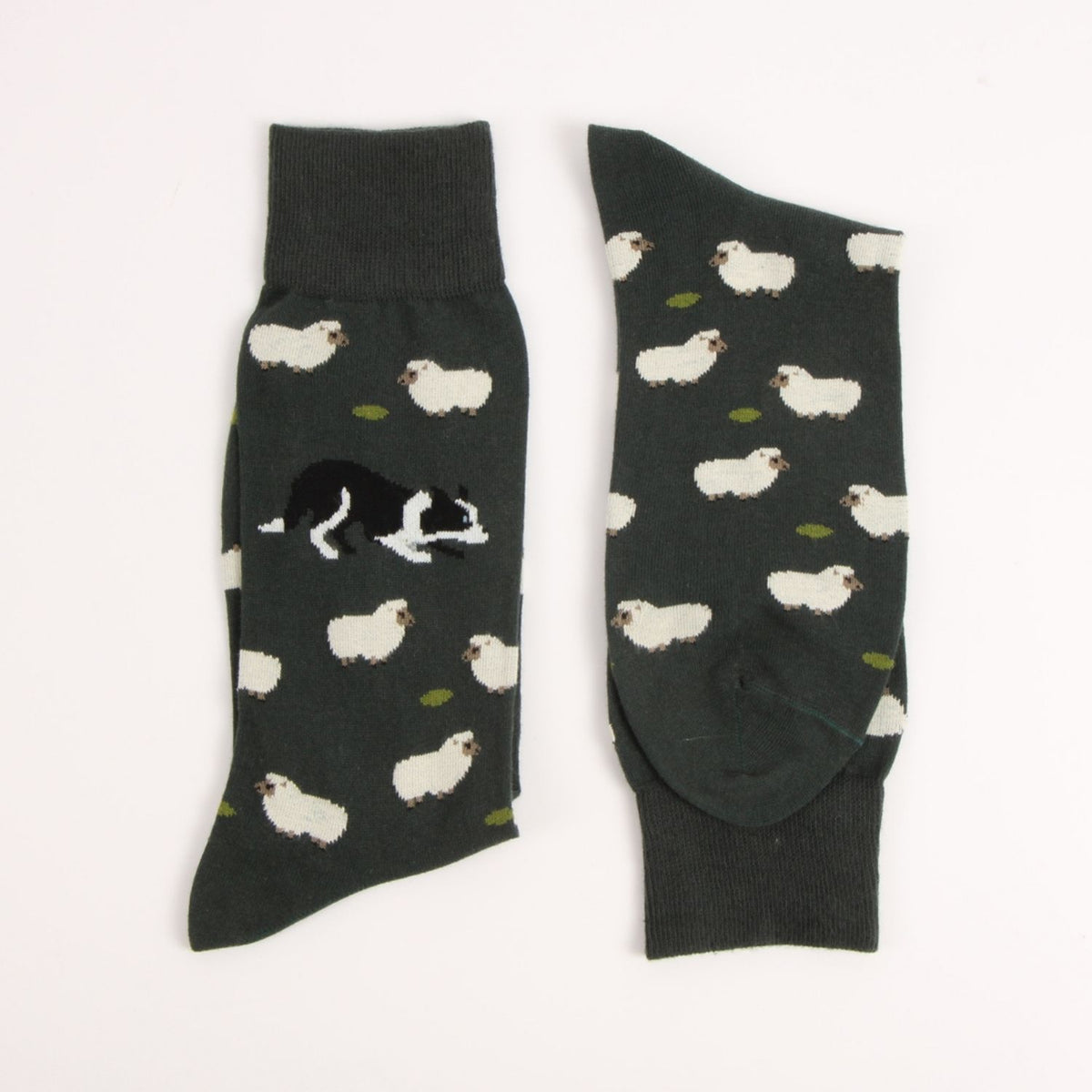 A pair of dark charcoal gray crew socks with a pattern of white sheep and a black-and-white dog, displayed flat against a white background.