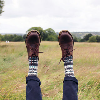 man wearing grey fair isle wool socks in a field 