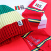 A set of Red Wall branded merchandise including a beanie hat and socks, with the logo featuring red, yellow, and green stripes, presented on a red background.