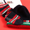 A set of Red Wall branded merchandise including a navy beanie with red and green stripes and a pair of matching socks, presented on a red background.