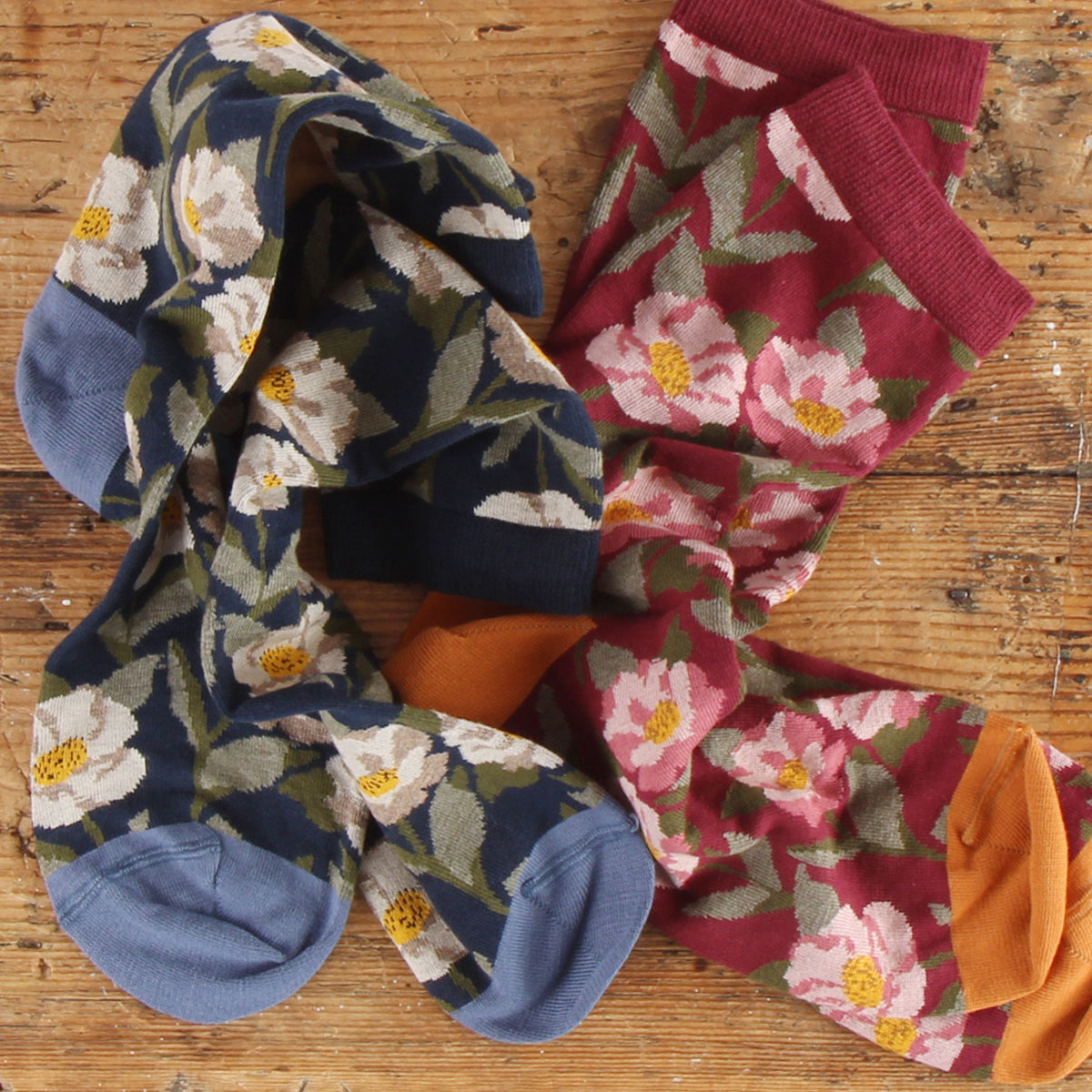Two pairs of floral-patterned socks on a wooden surface