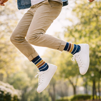 man jumping in the air wearing striped cotton socks and white trainers.