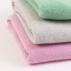 Stack of folded pastel-colored ponchos on a light background