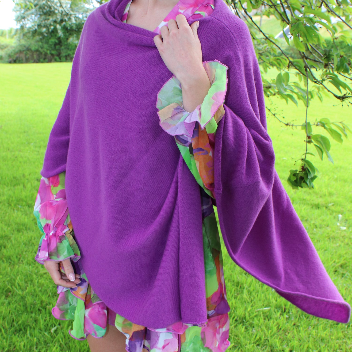 Person wearing a purple poncho with colorful sleeves in an outdoor setting